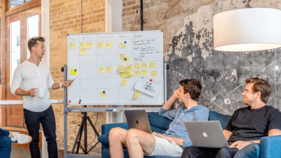 IT team collaborating around a project whiteboard