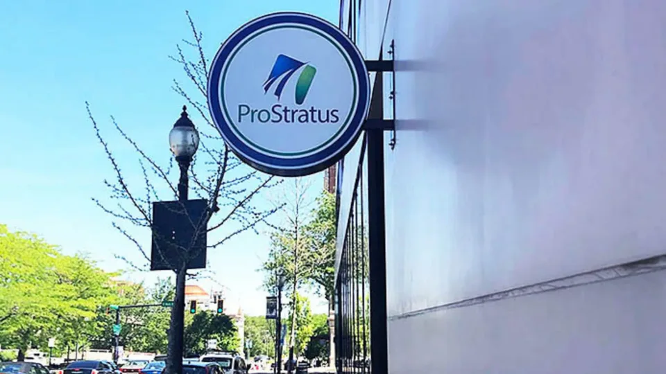 Round ProStratus sign mounted above a sidewalk outside the office.